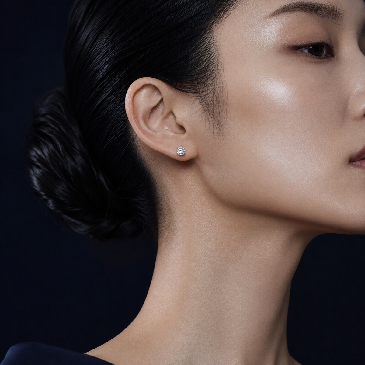 Lucent four-prong round moissanite stud earring worn on a model's ear
