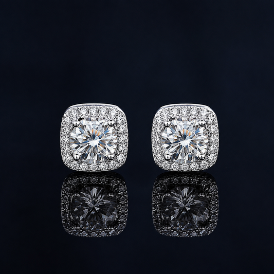 Pair of Orbit cushion-halo moissanite stud earrings on a dark reflective surface